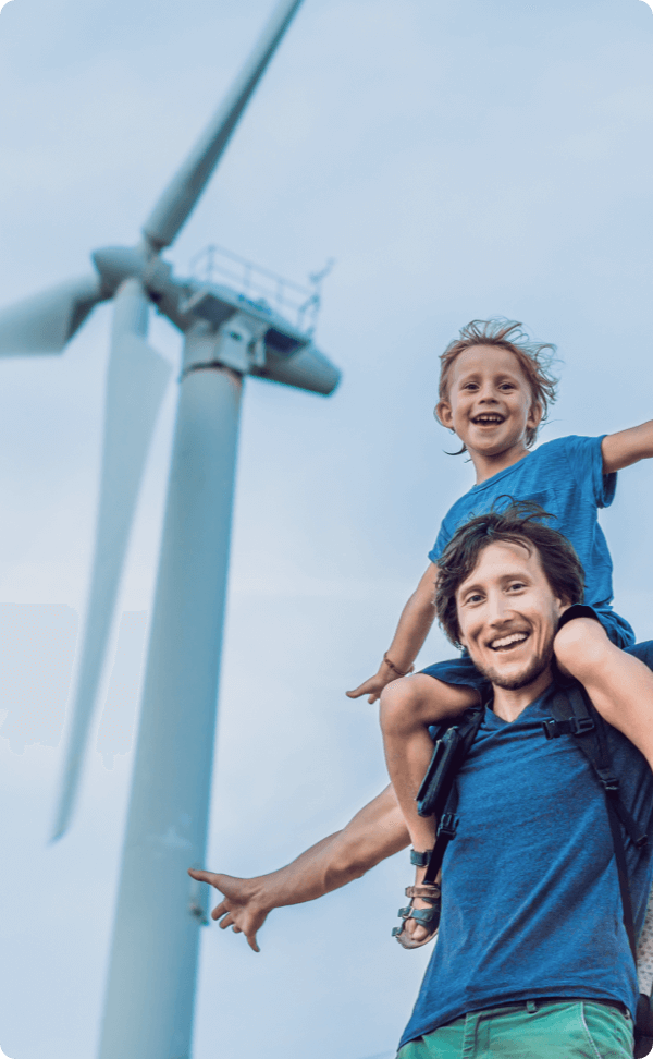 Portrait of father holding son on shoulders next to windmill
