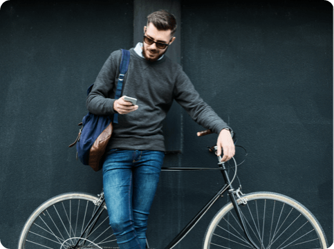 Man standing with a bike, using a mobile device